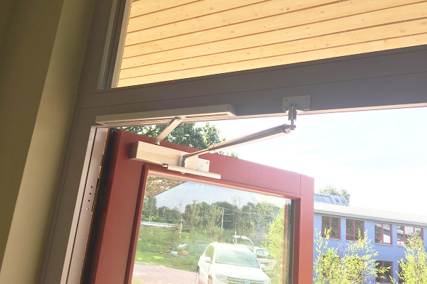 Limitador de apertura con cierrapuertas aéreo en puerta de escuela